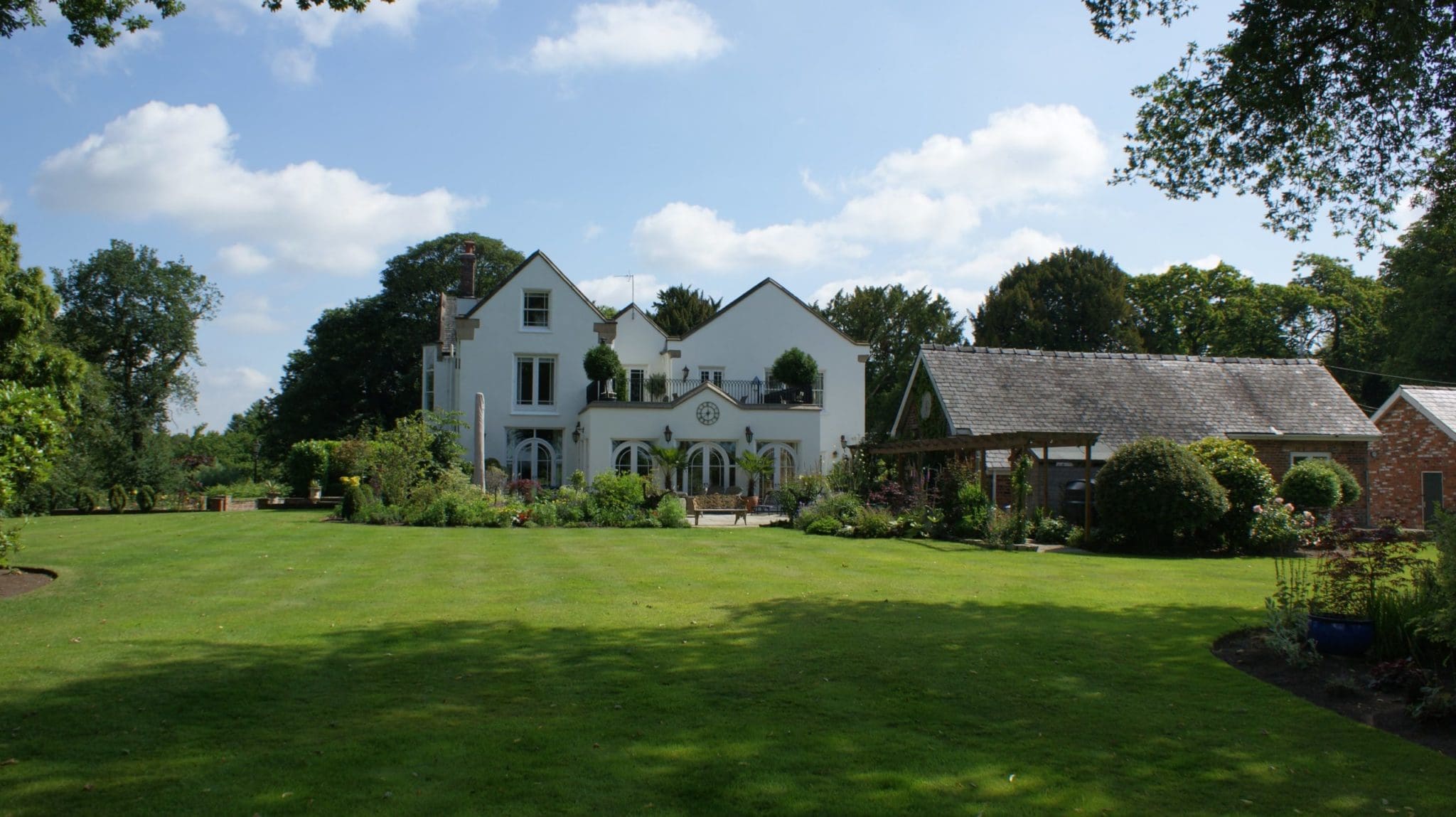 a large white house sitting on top of a lush green field.