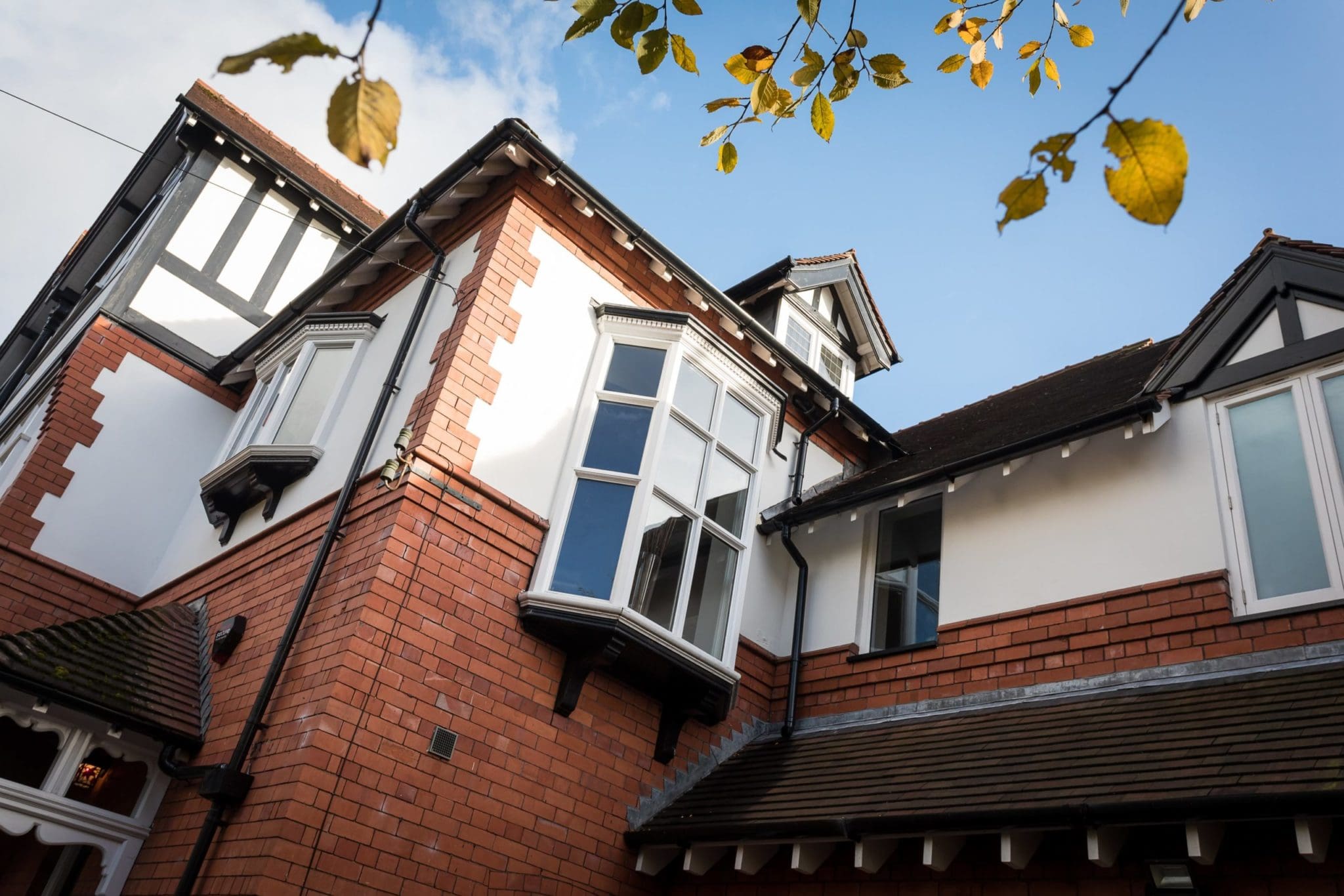 a red brick house with white windows and a brown roof.