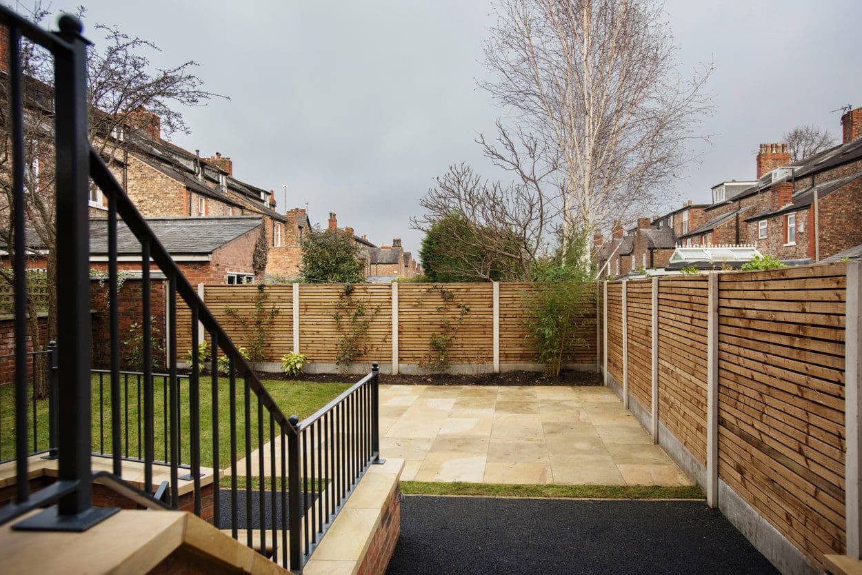 a back yard with a wooden fence and black iron railing.