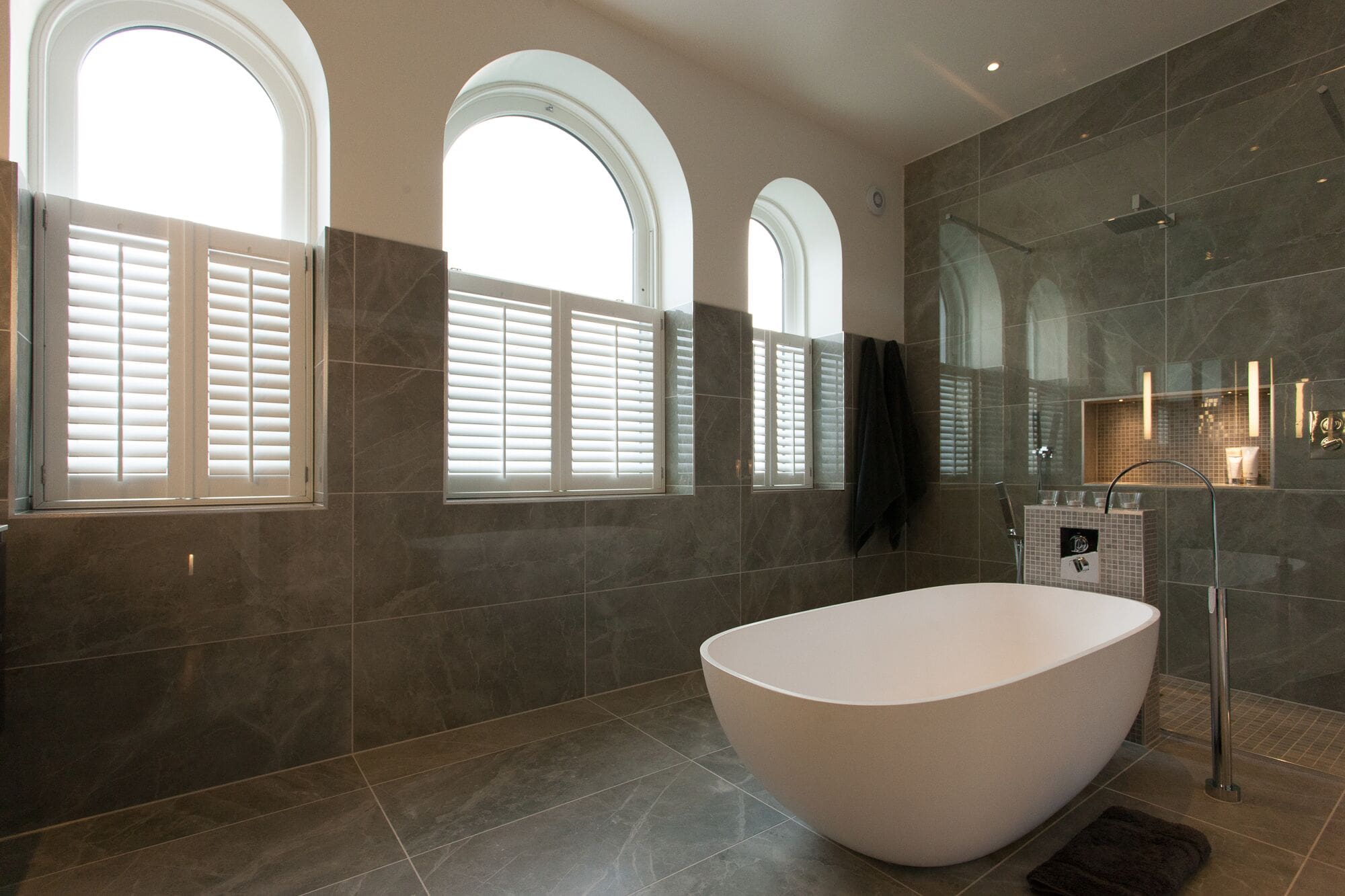 a bathtub in a bathroom with three windows.