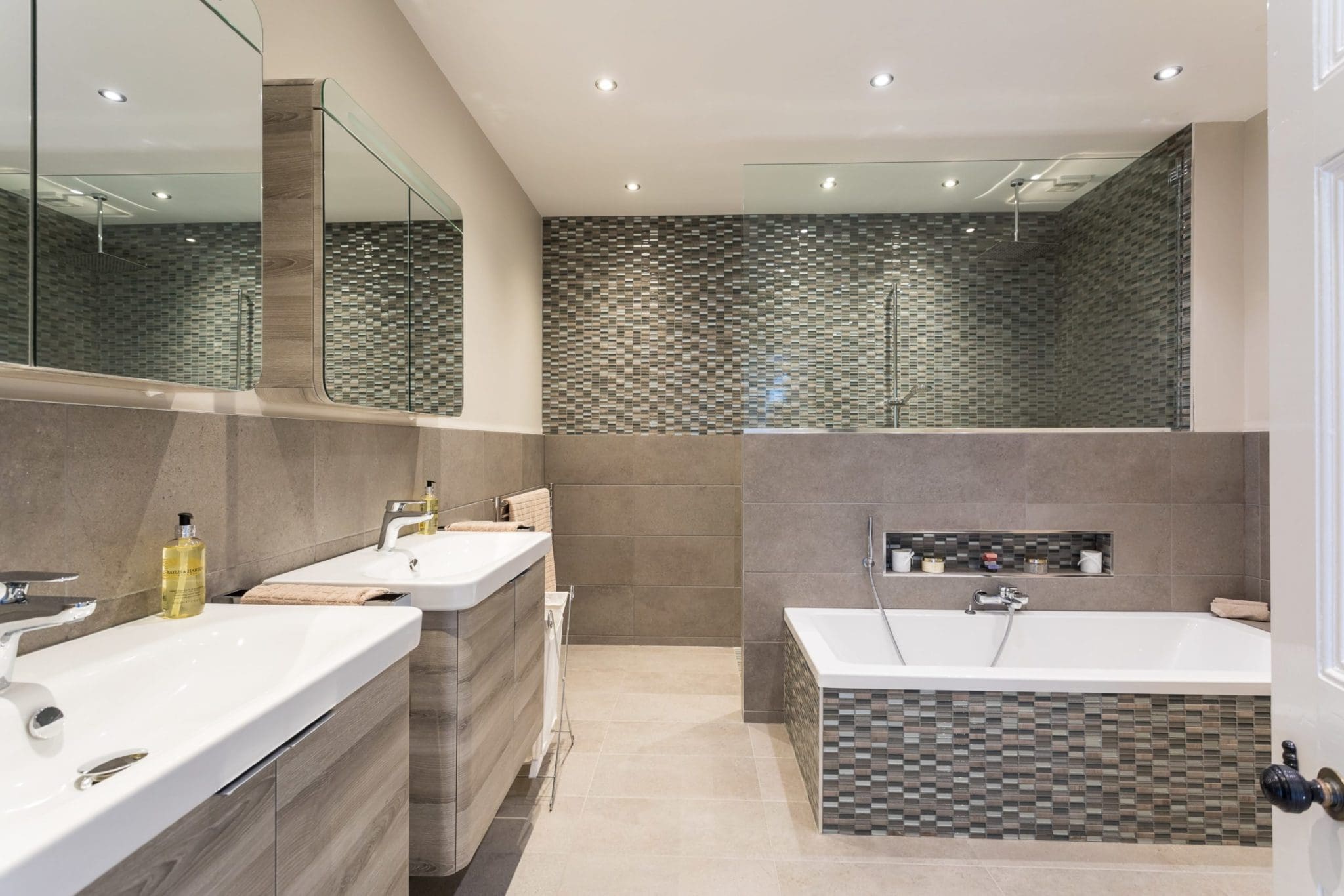 a bathroom with a tub, sink, and mirror.
