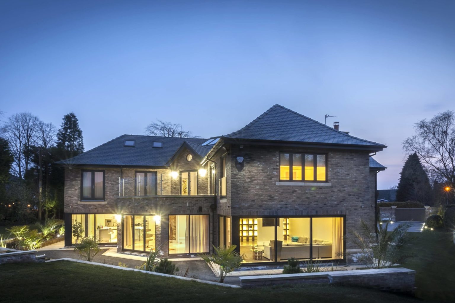 a large brick house showing the house lights in the night