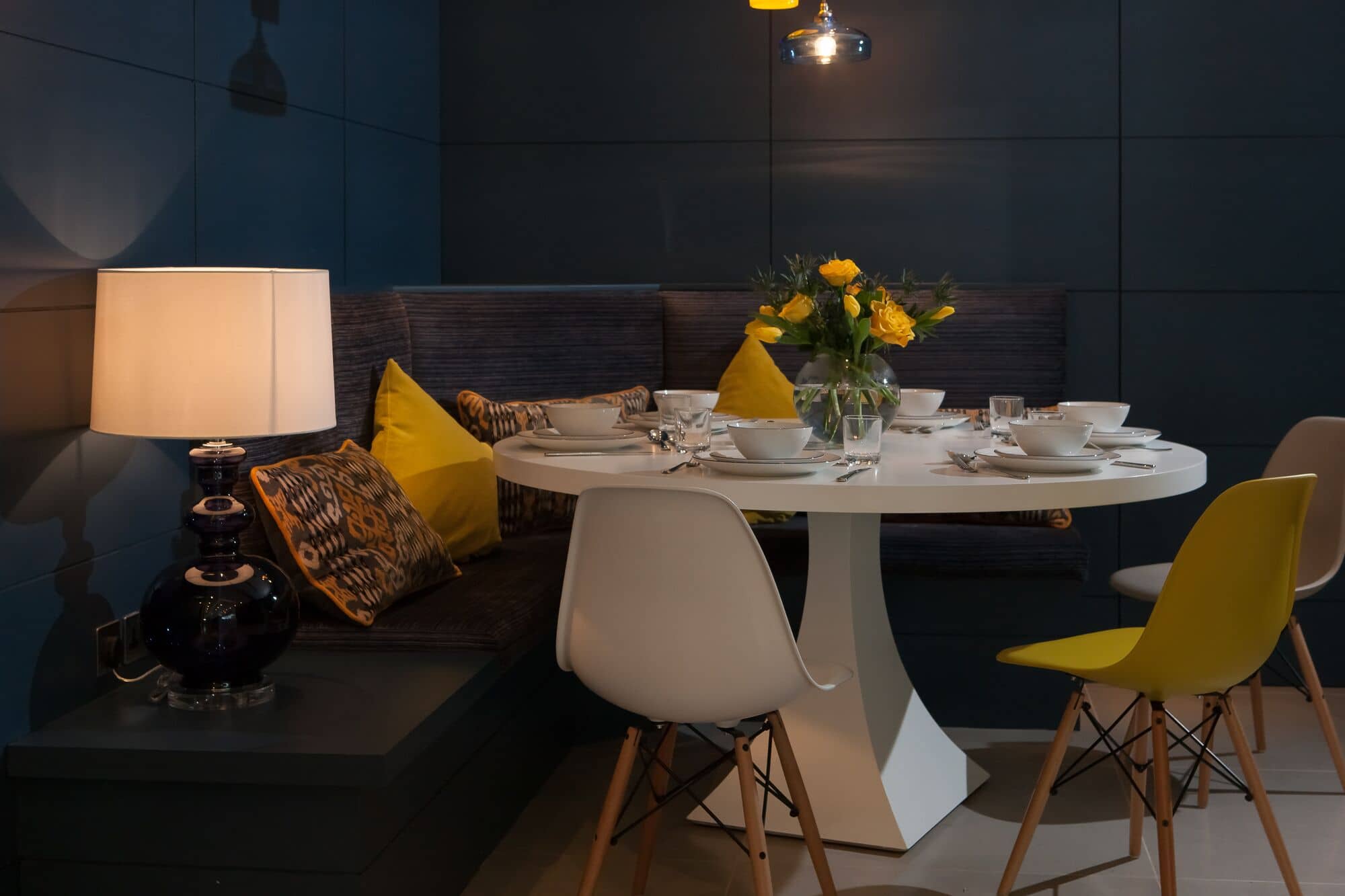 a white table with yellow chairs and a vase of flowers.