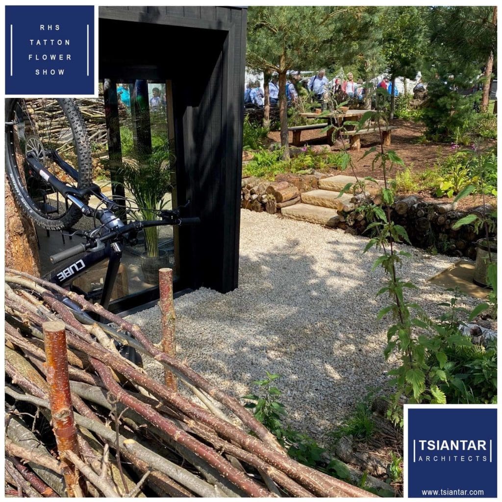 A bike is parked in a wooden shed in a garden.