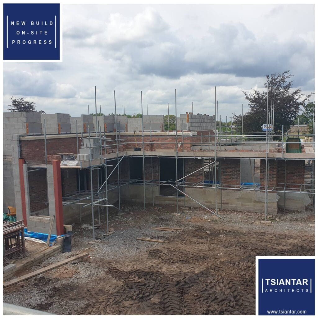 A newly constructed lakeside house with scaffolding in the background.