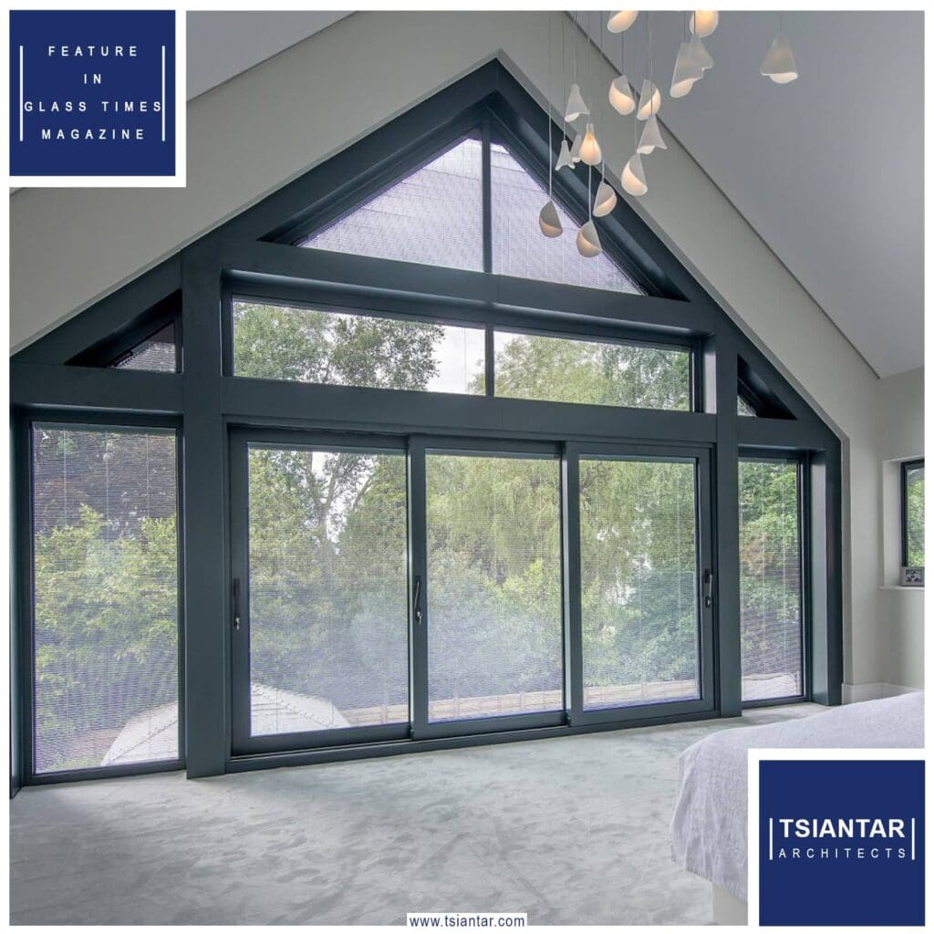 A bedroom featured in a Glass Times magazine article, showcasing sliding glass doors and a comfortable bed.