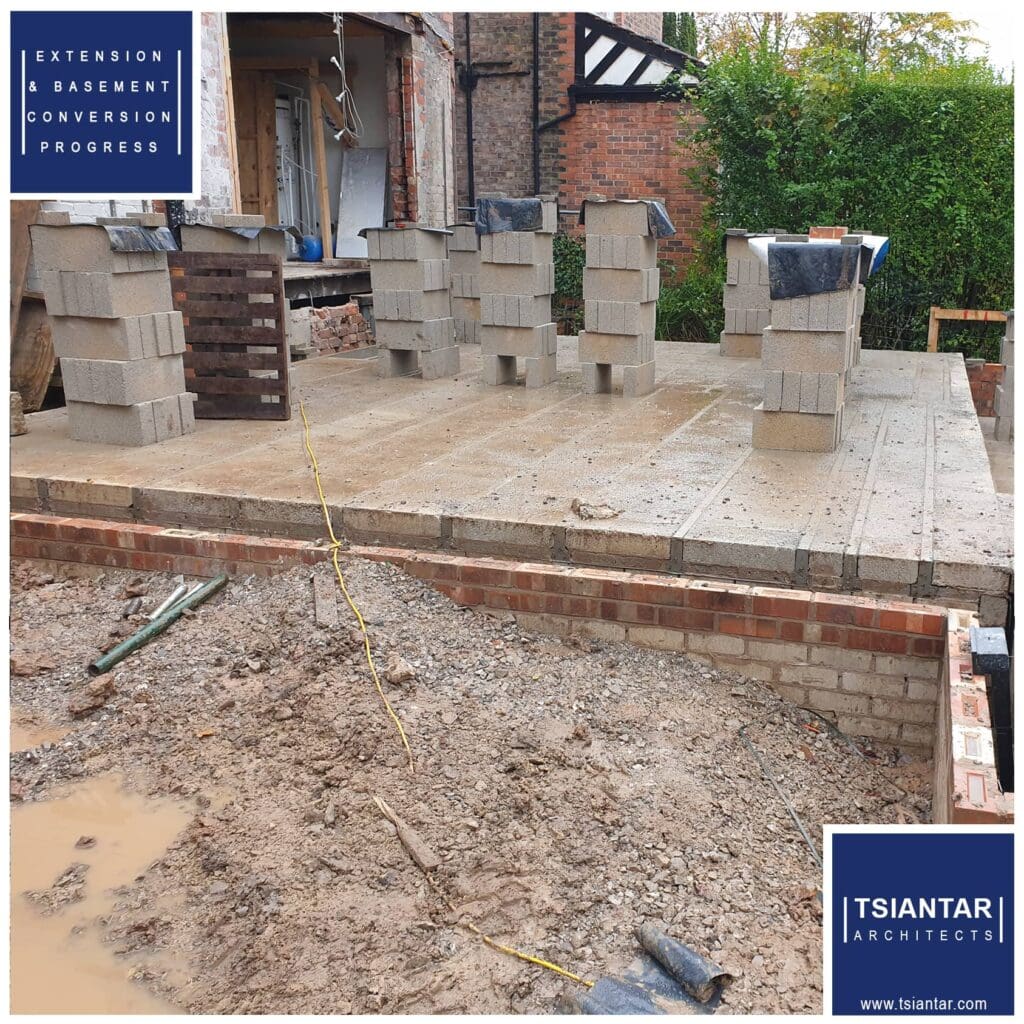 Progress: A house is being built with concrete blocks and bricks. The construction is steadily advancing as the walls are taking form using a combination of sturdy concrete blocks and traditional bricks. Materials have been carefully