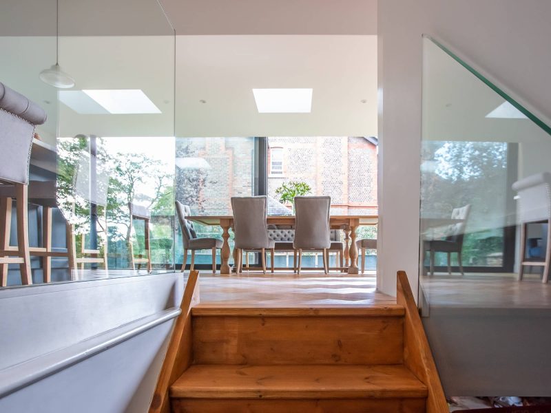 a staircase leading up to a dining room table and chairs.