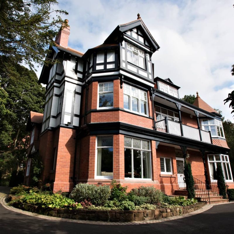 A large black and white Victorian house undergoing restoration.